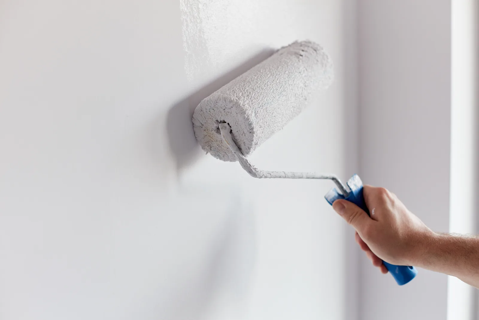 Paint roller applying fresh paint to a wall