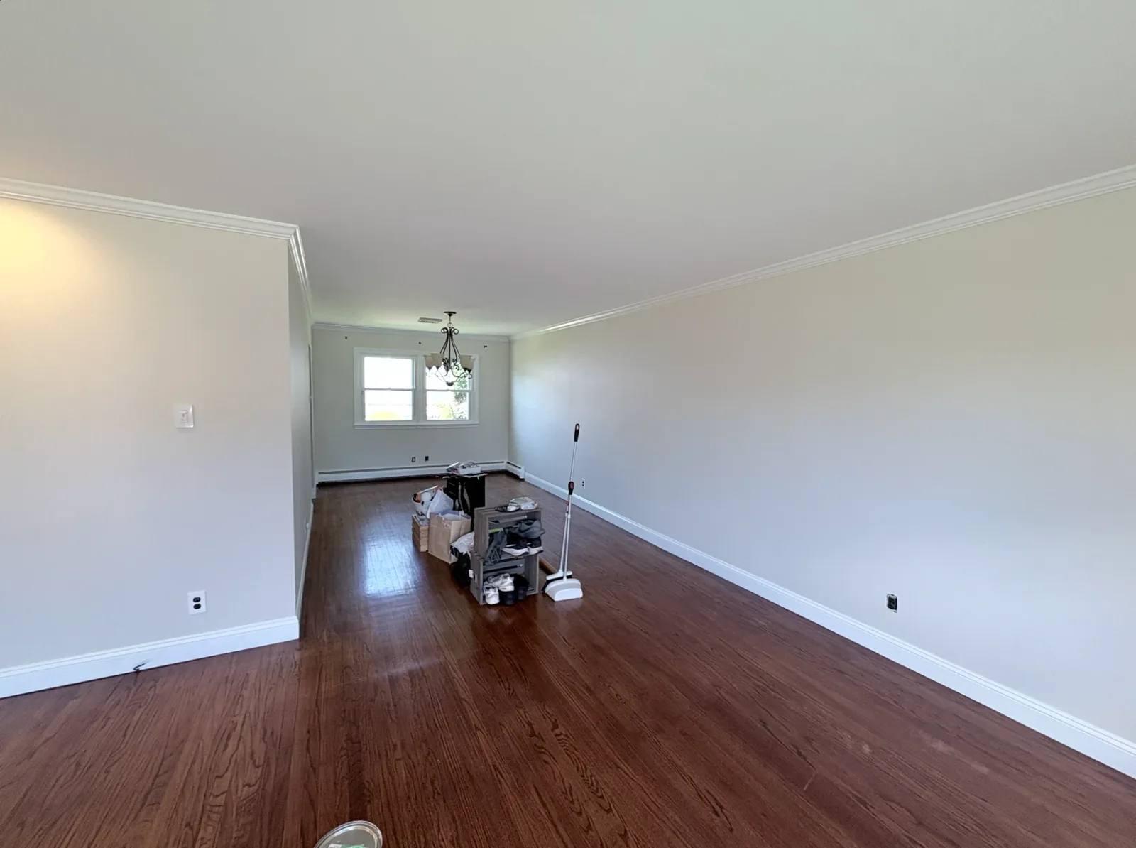 Living room with hardwood floors and neutral walls with white crown molding and trim
