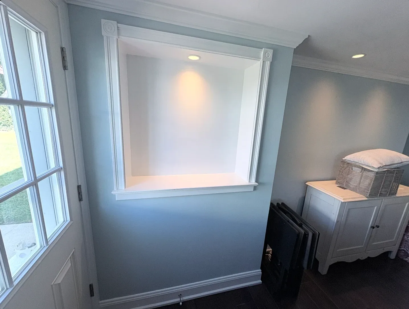 Wall niche with white trim molding painted against a pale blue wall near the front entry