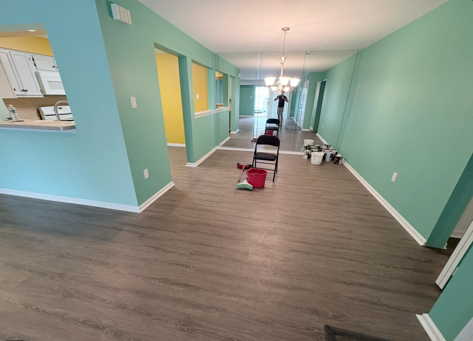 Open concept living and dining room painted mint green with a yellow accent nook and white trim