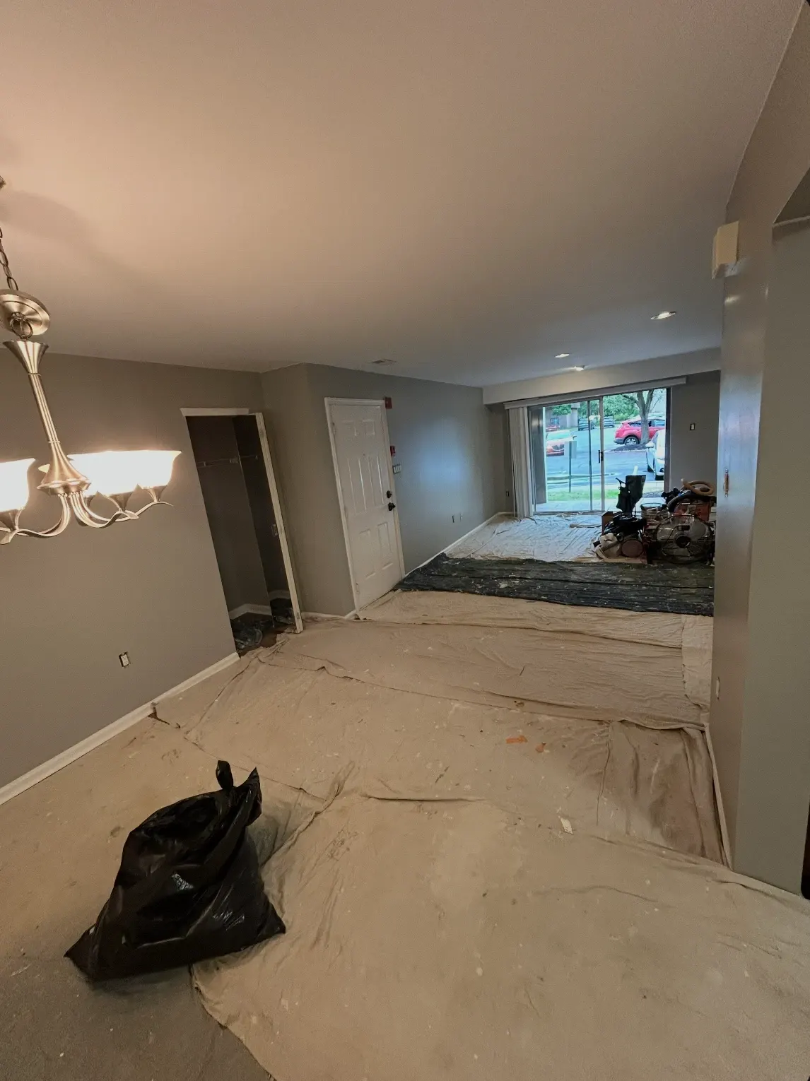 Room mid-project with floors fully covered in drop cloths and supplies staged along the wall