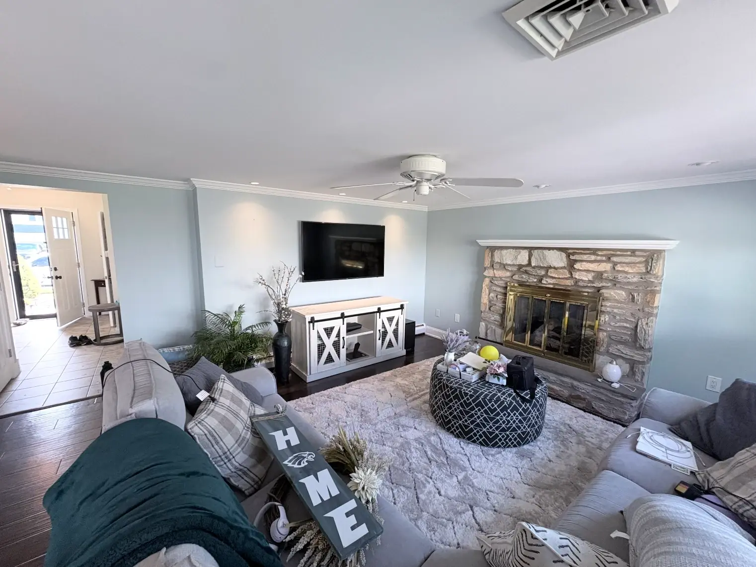 Living room painted soft blue gray with a stone fireplace and white ceiling trim