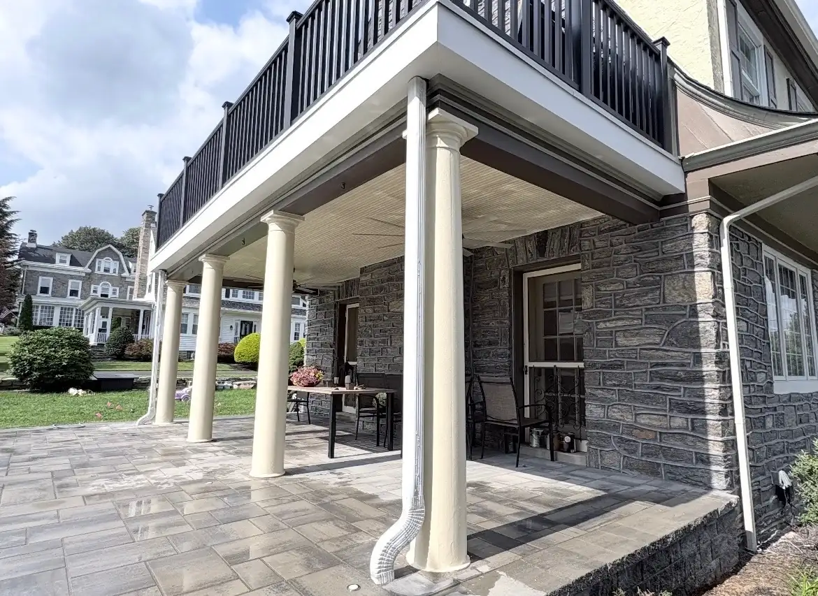 Front porch columns and balcony railing freshly painted on a stone rowhome exterior