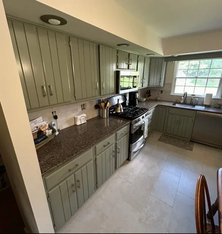 Kitchen with cabinets refinished in sage green, granite countertops, and tile backsplash
