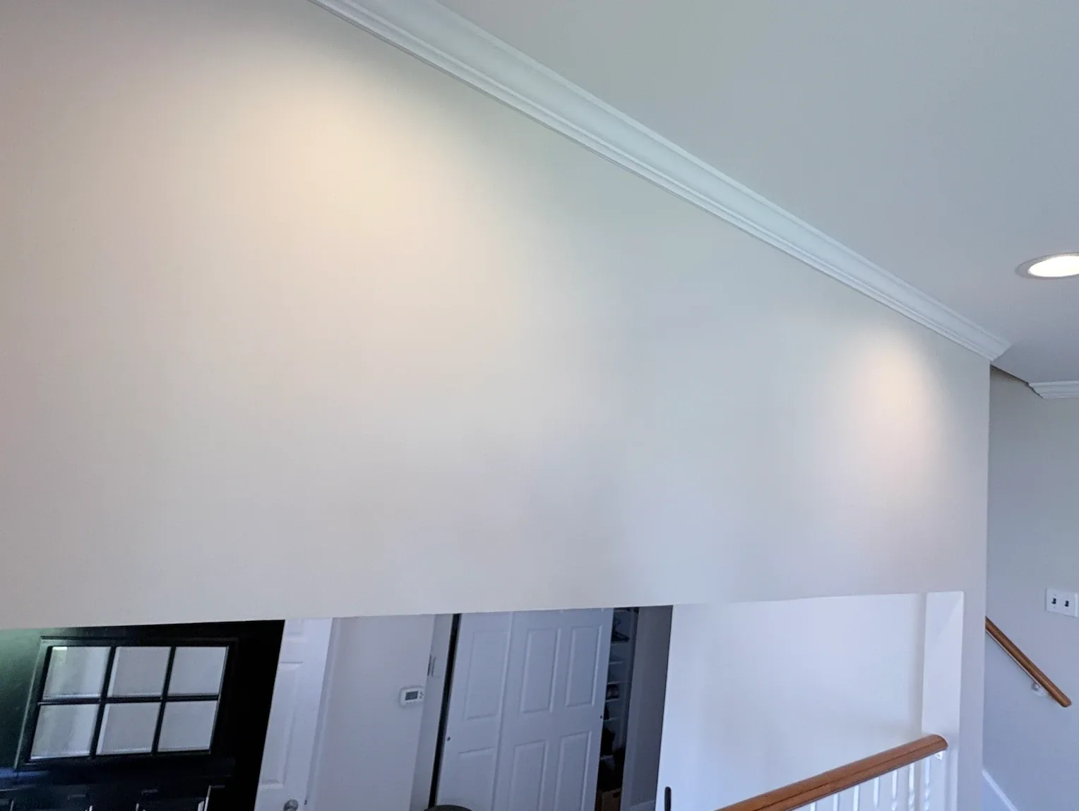 Vaulted stairwell ceiling with white crown molding and freshly painted walls