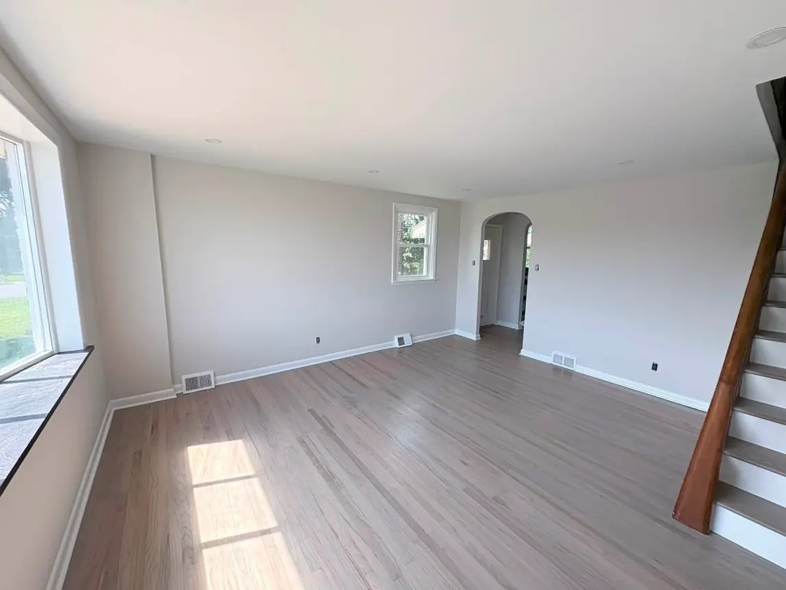 The same living room finished in a warm gray with white trim and ceiling and refinished wood floors